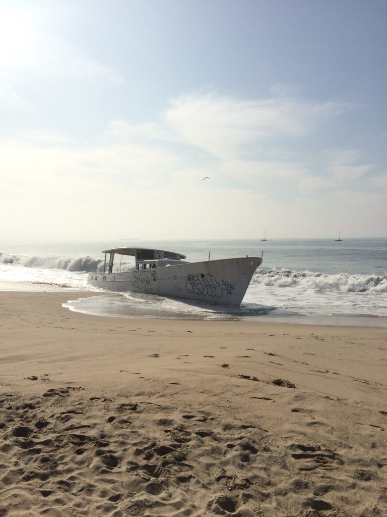 A boat with some graffiti on it run aground on Toes Beach (Playa Del Rey, California)