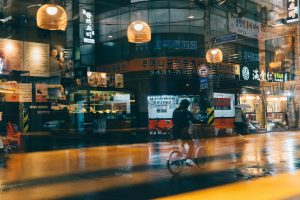 Cyclists in the rain at night in front of a cafe in Korea