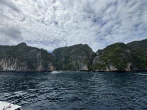 A scenic view from a boat showcasing rugged rocky cliffs rising majestically from the water's edge.