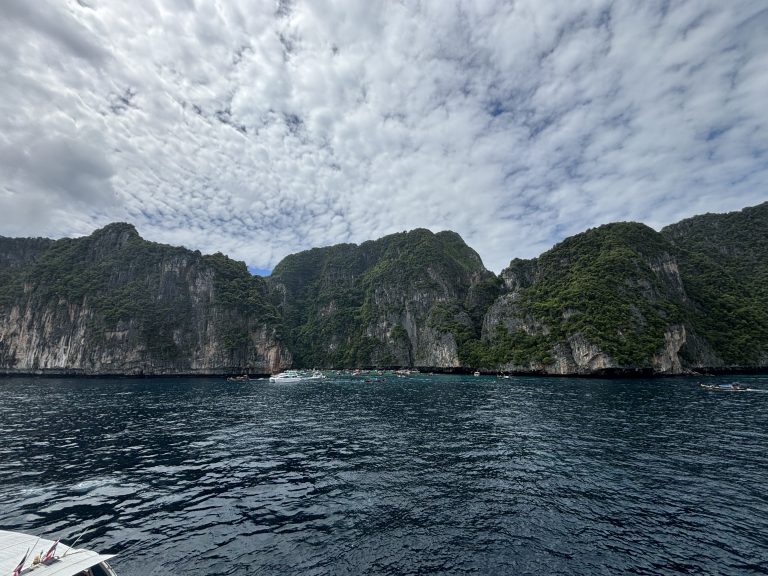 A scenic view from a boat showcasing rugged rocky cliffs rising majestically from the water’s edge.