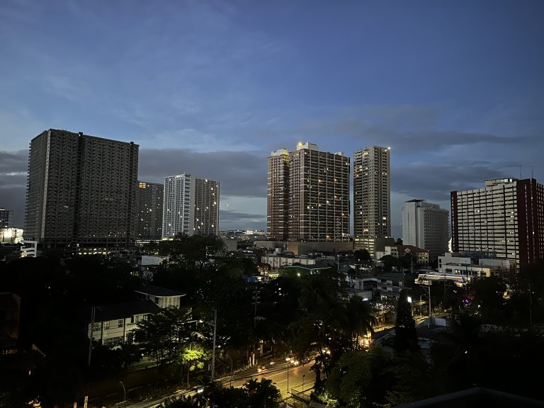 Manila, Philippines—A city skyline at dusk with several tall buildings illuminated.