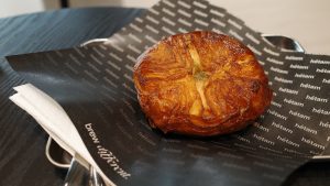 A delectable pastry resting on a sheet of black paper, showcasing its golden-brown crust and inviting texture. 
