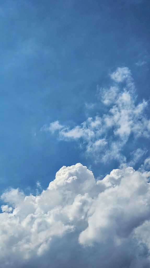 A clear blue sky with large, fluffy white clouds.