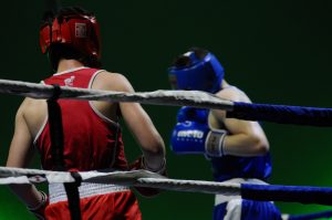 Two young boxers wearing protection equipment training in a boxing ring.