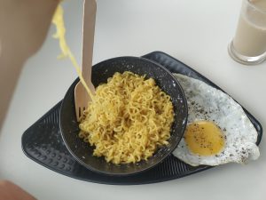 A bowl of flavorful instant noodles, topped with a fried egg, ready for a quick and satisfying meal.