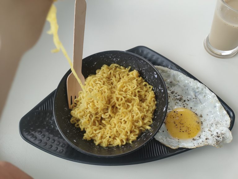 A bowl of flavorful instant noodles, topped with a fried egg, ready for a quick and satisfying meal.