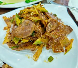 
A plate of sliced Chinese buff Chilly mixed with vegetables, seasoned with spices, served on a white dish.