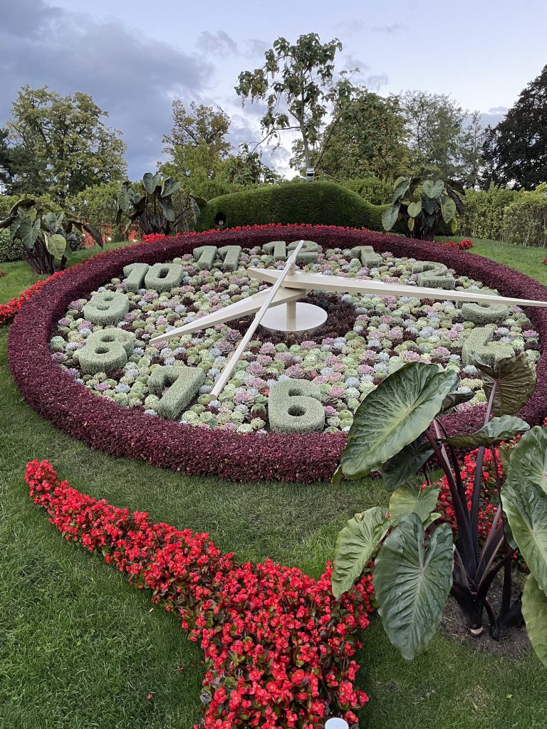 A large outdoor clock made entirely of plants and flowers, with numbers crafted from moss and succulents.