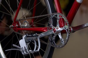 Detail of the crankset and pedals of a red bicycle.