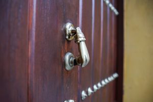 A close-up of a decorative brass door knocker shaped like a hand on a wooden door, with studs lining the door.