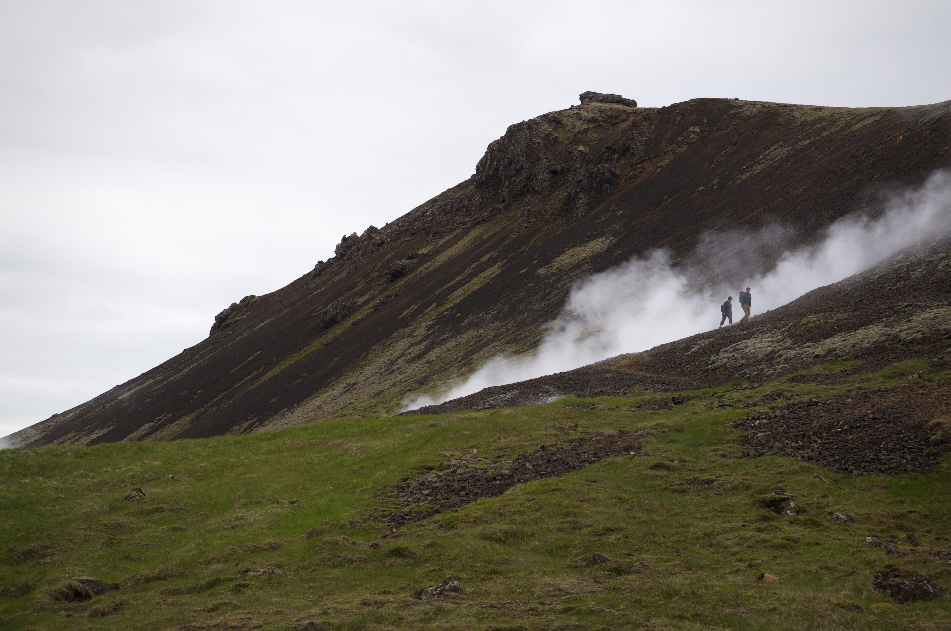 A couple of hikers walking on a hillside in a national park in Iceland.