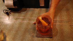 A hand holding a refreshing drink garnished with a vibrant orange slice, showcasing a delightful beverage experience.
