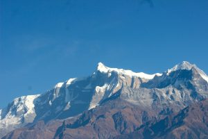 A majestic mountain range with snow-capped peaks under a clear blue sky.