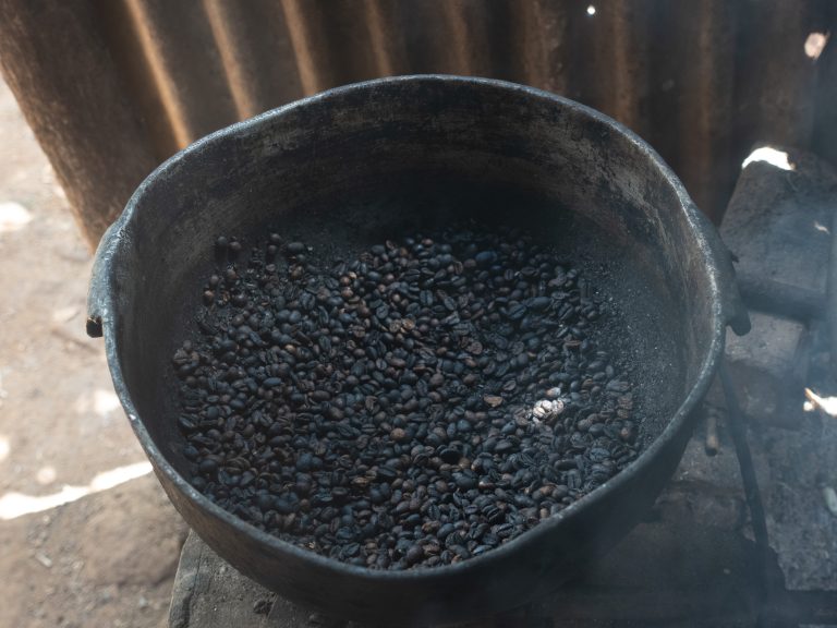 Metal pot with roasted coffee beans on a stove, surrounded by rustic and earthy surroundings. Vi?ales, Cuba.