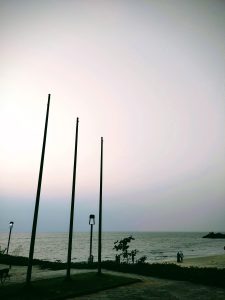 The empty flagpoles, silhouetted against the fading light, create a sense of peaceful solitude along the shoreline.