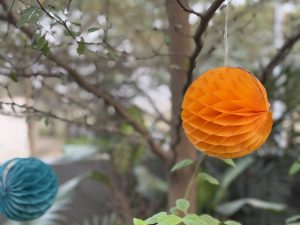  Colorful orange and blue paper ball  decorations elegantly draped from a tree, creating a cheerful ambiance.
