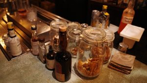 A bar counter displaying an array of bottles and jars, showcasing a variety of beverages and ingredients.
