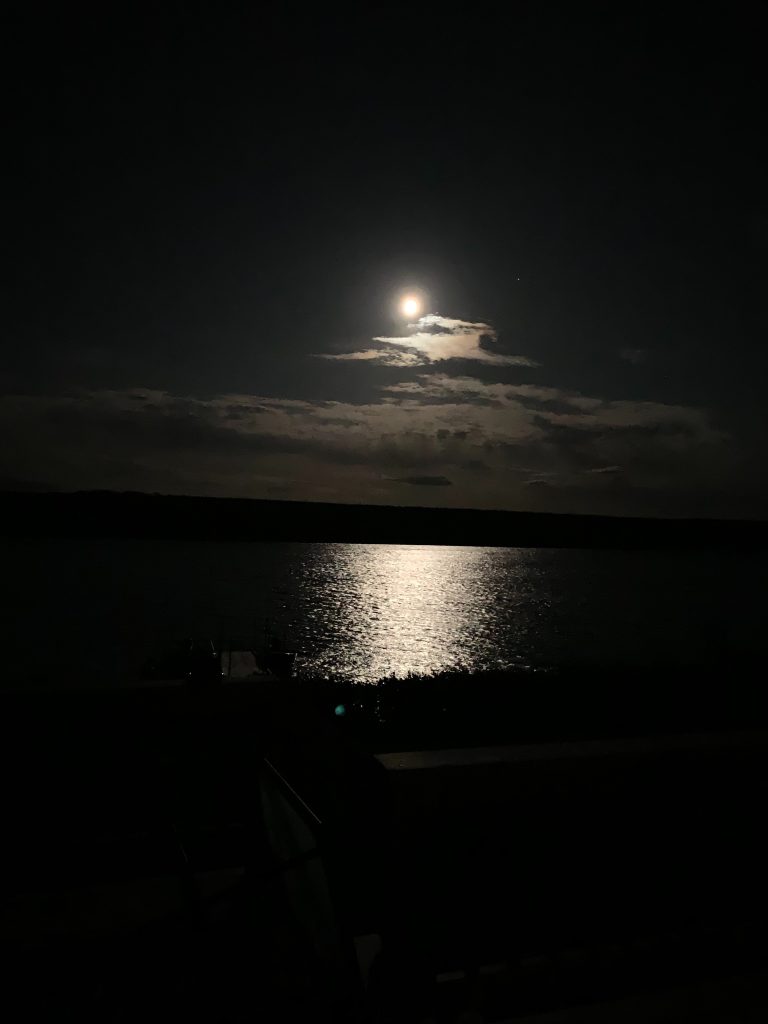 The moon shines brightly above a cottage on the shore of Gambo Pond, Newfoundland, Canada.