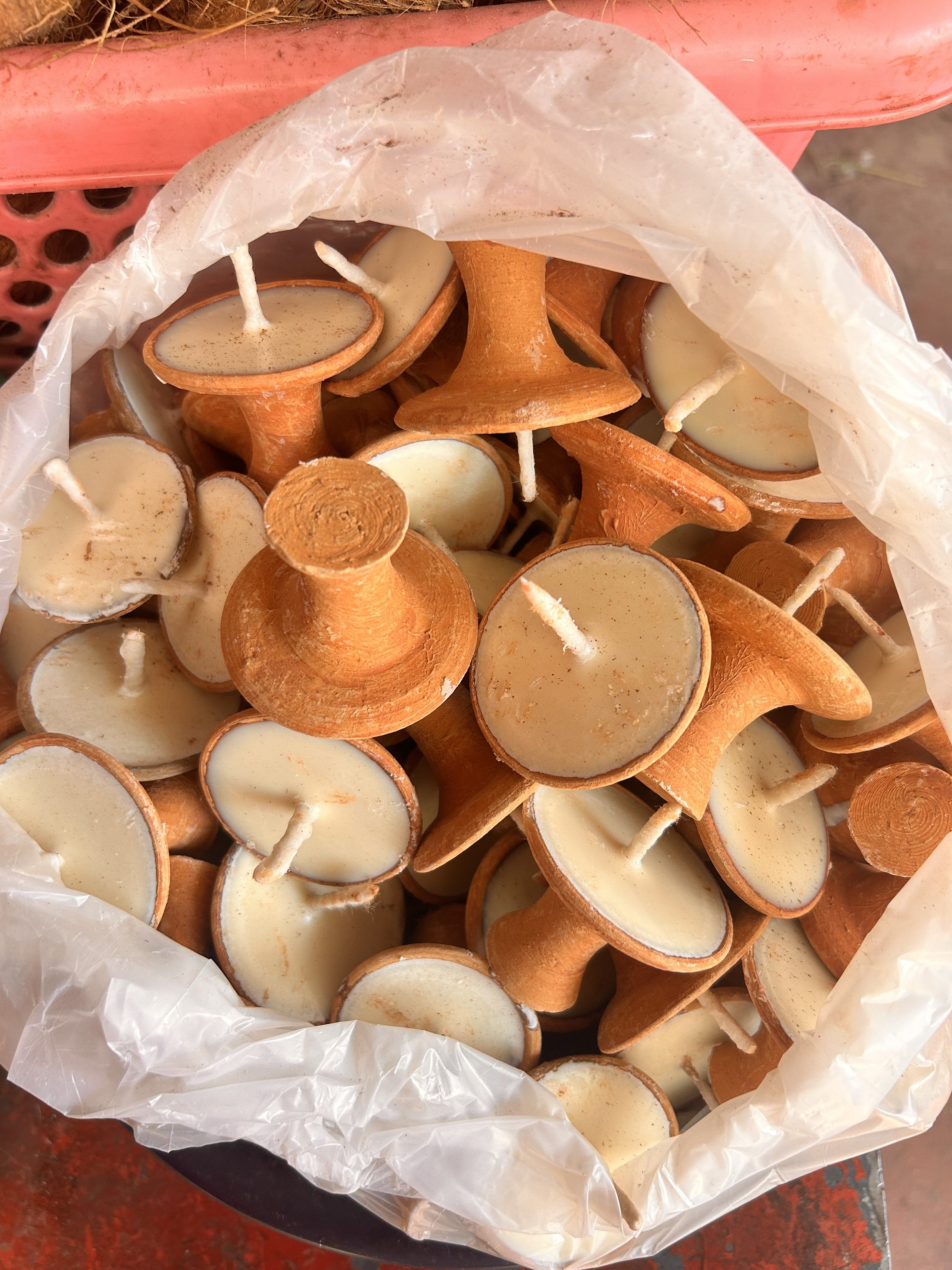 A plastic bag filled with brown, handmade candles resembling upside-down mushrooms with wicks