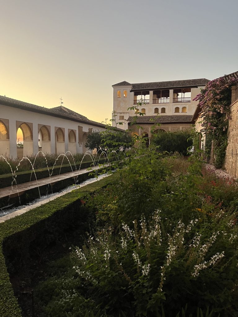 Generalife Palace in Granada at sunset with the fountains flowing and the sun hidden between the columns