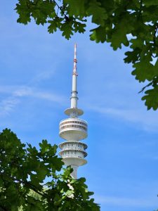 The Olympic Tower (Olympiaturm) in Munich, Germany, framed by green leaves. 