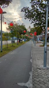 A peaceful street adorned with red Chinese lanterns and decorative string lights, creating a festive and welcoming ambiance along the pedestrian walkway.