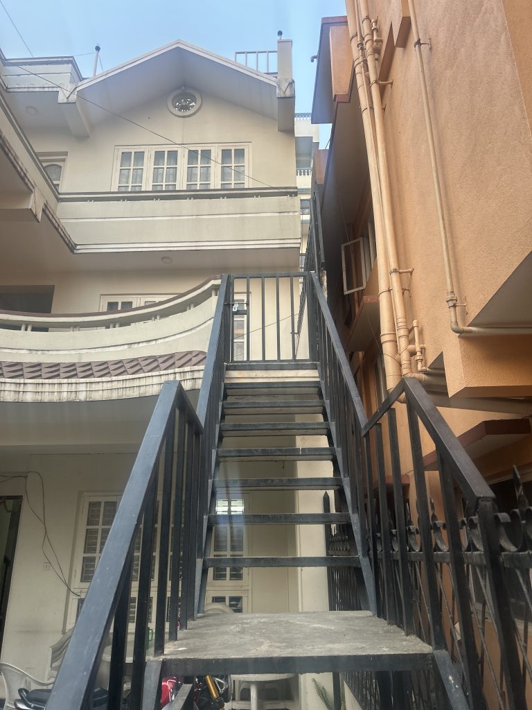 A metal staircase with black railings leads up to the second floor of a residential building.