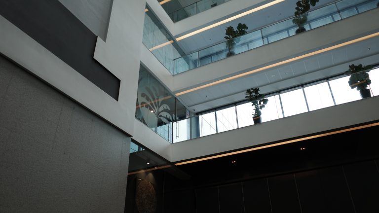 The interior of a building reveals multiple floor levels, highlighting its architectural details while blue sky is visible through the windows.