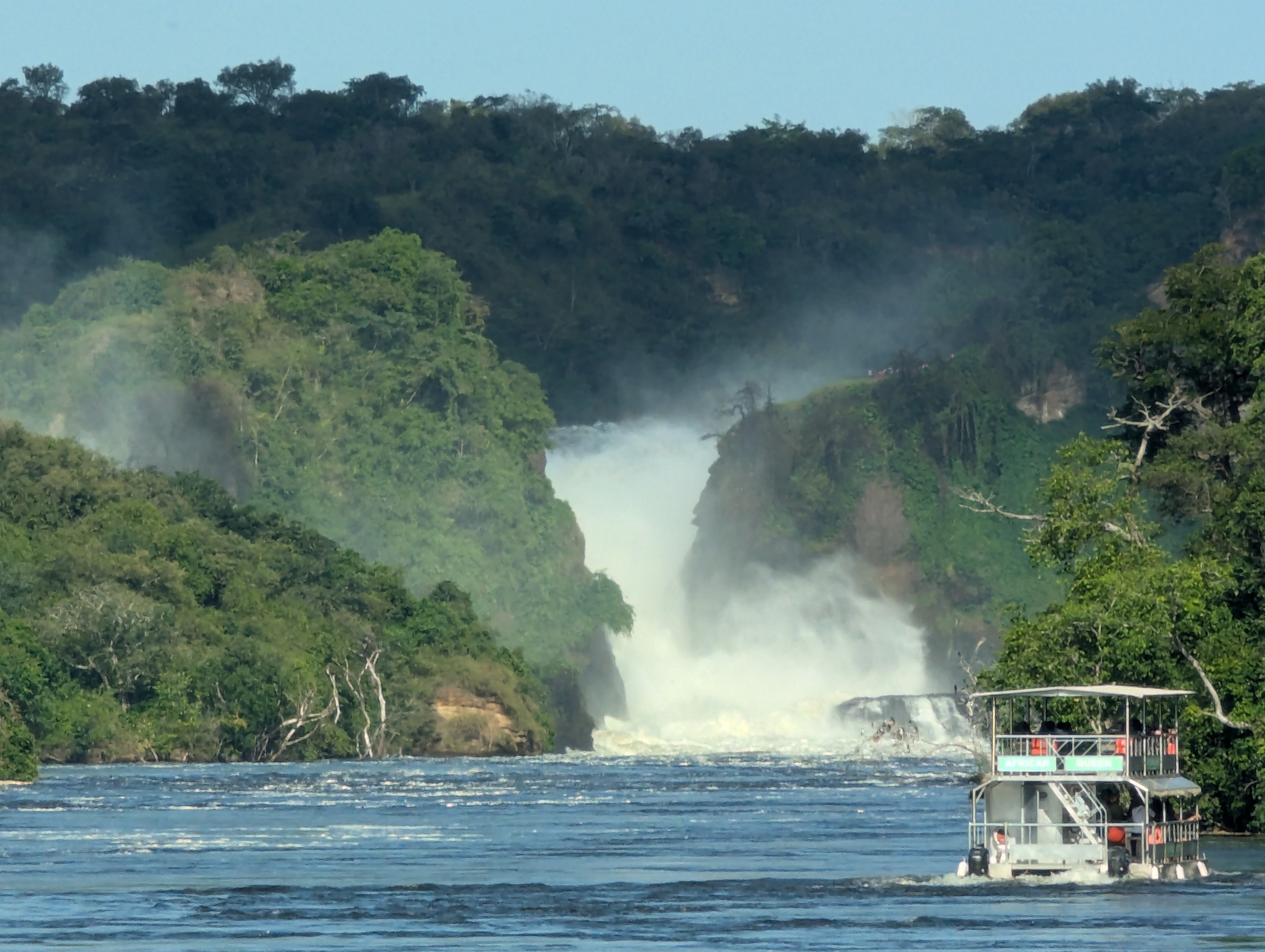 A waterfall, water gushing between two cliffs with a boat of people watching