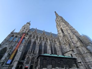 The St. Stephen's Cathedral in Vienna, Austria. The cathedral's intricate Gothic architecture is prominently displayed, showcasing its spires, detailed stonework, and colorful tile roof.