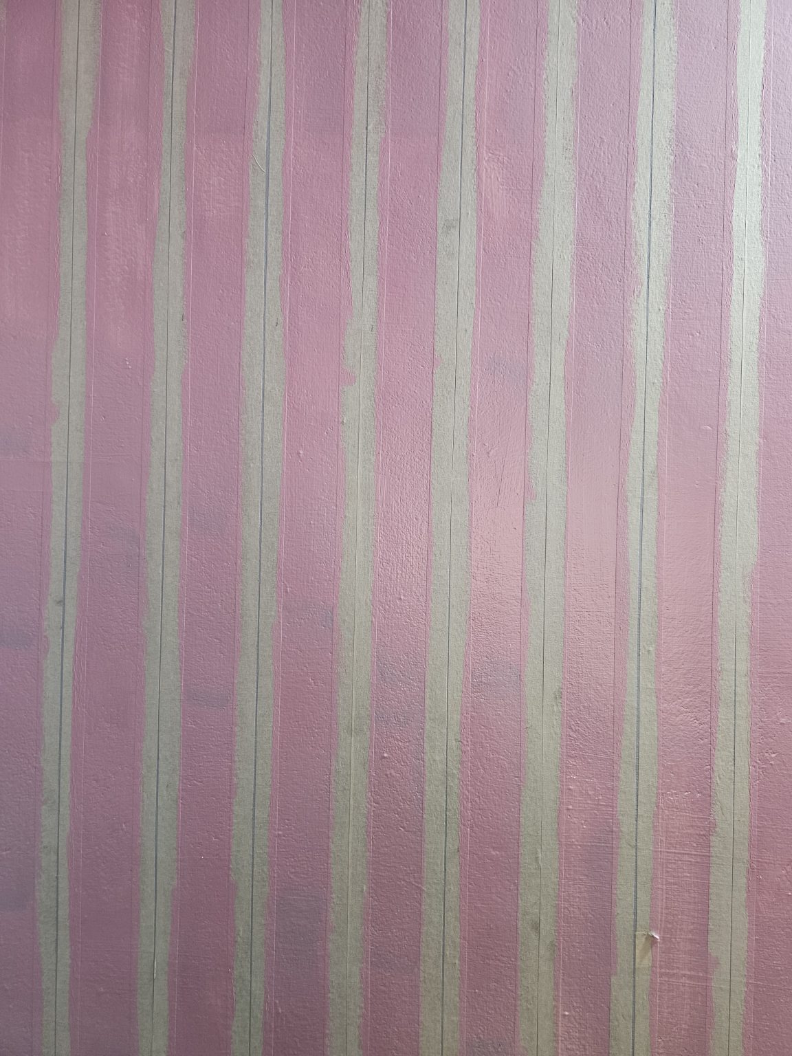 A textured wall, painted pink and marked with white masking tape stripes, is undergoing preparation for a striped paint finish. Captured from Perumanna, Kozhikode, Kerala.