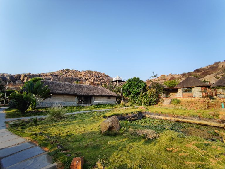 Traditional Indian Mud Houses, green loan in front and Stone paved path in between.