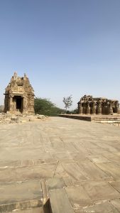 Ancient stone temples of Kiradu in Rajasthan, India, with intricate carvings and partially ruined structures standing against a clear blue sky, surrounded by a dry landscape.