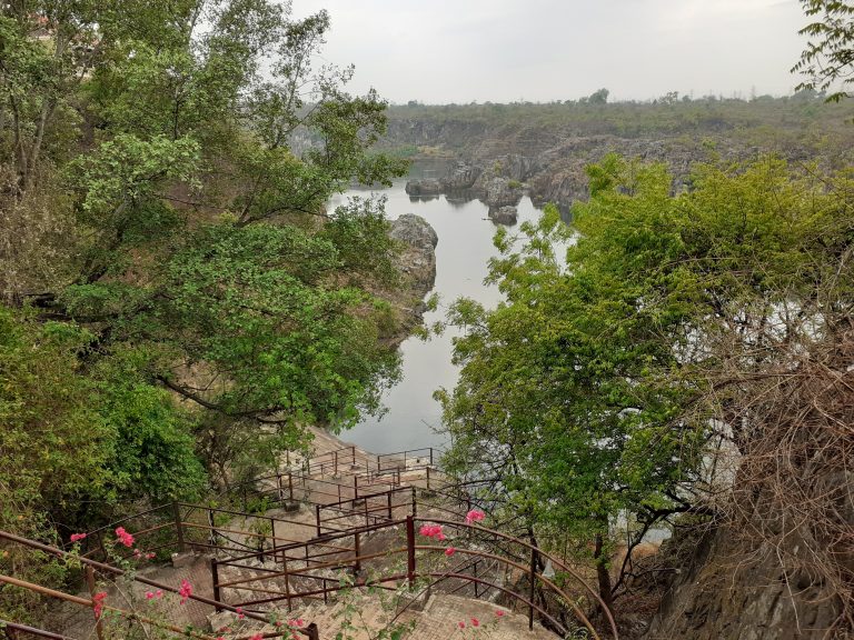 A scenic view of a natural landscape featuring a body of water surrounded by rocky hills and lush greenery.