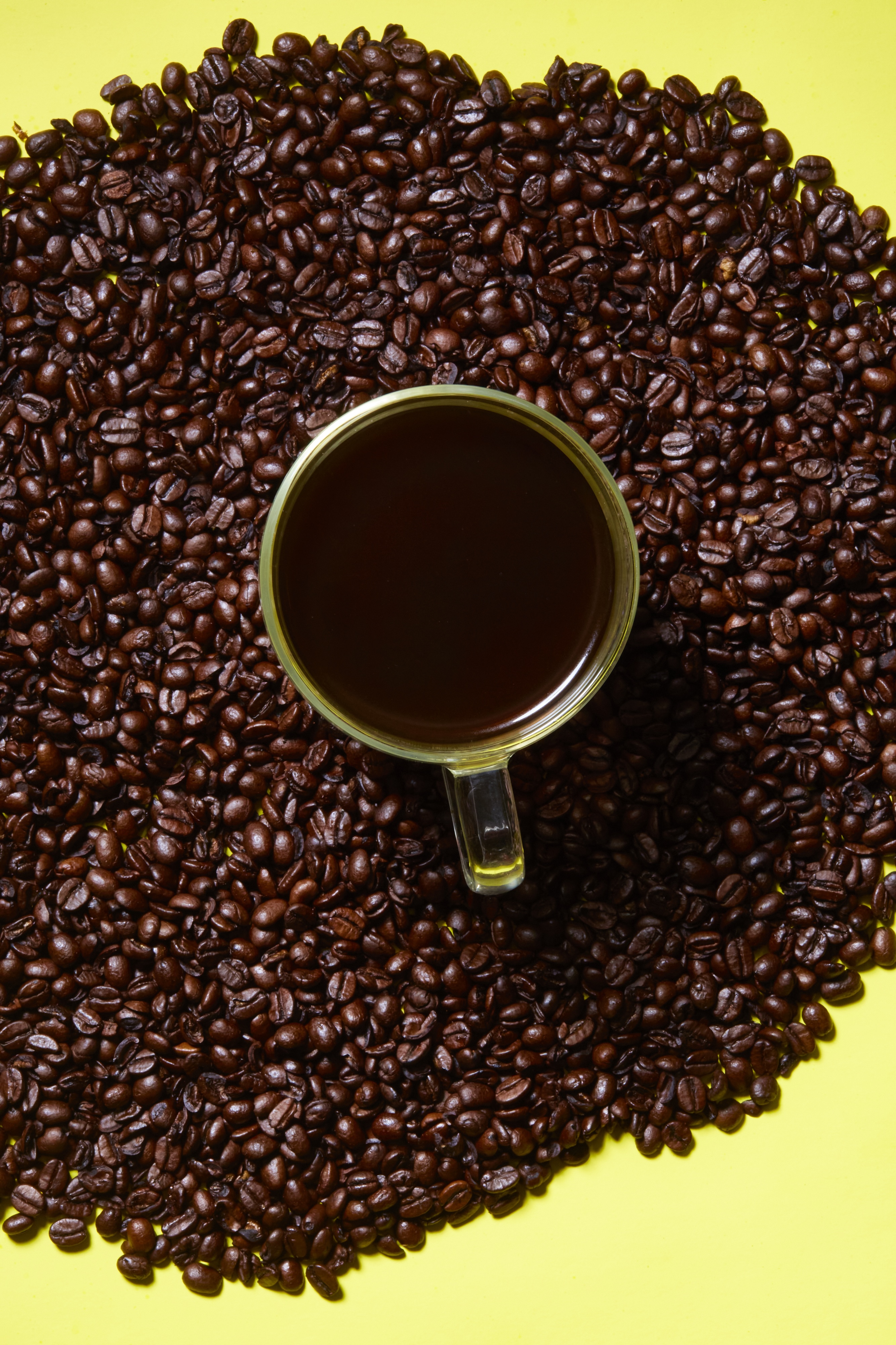 Coffee cup and coffee beans on a yellow background.