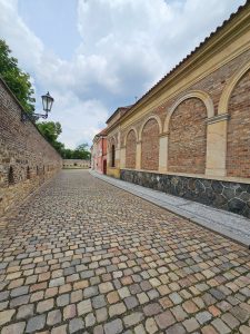 A cobblestone pathway leading toward a brick building with arched windows, located at Vyšehrad Castle in Prague.