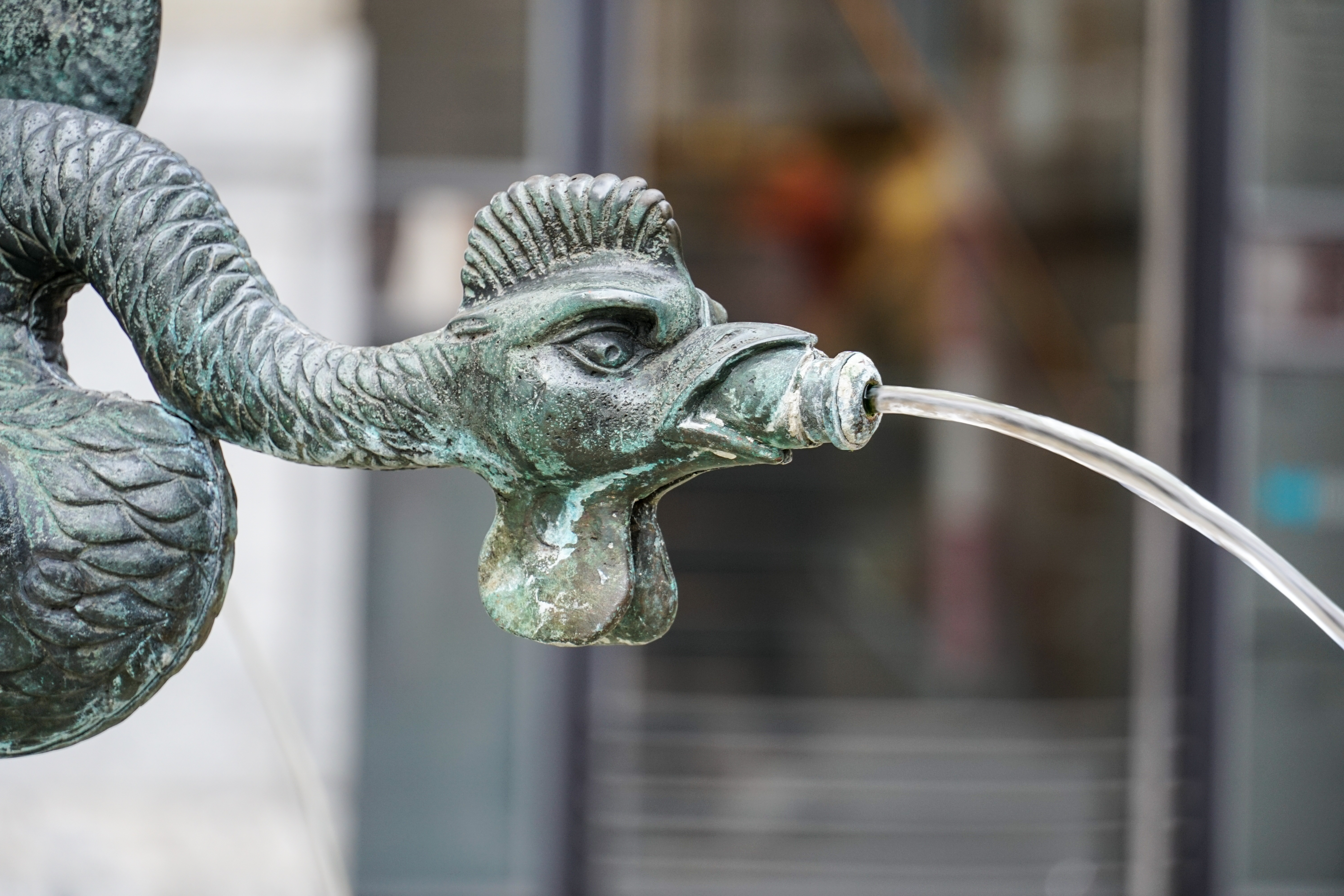Bronze fountain sculpture shaped like a mythical creature with water spouting from its mouth.