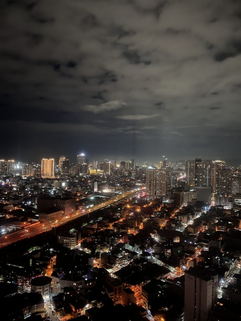 A stunning aerial night view of Manila, Philippines, showcasing a brightly lit highway cutting through the dense urban landscape.