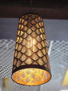 A hanging lamp with a geometric design casts a warm glow. Captured from an electrical shop in Kozhikode.