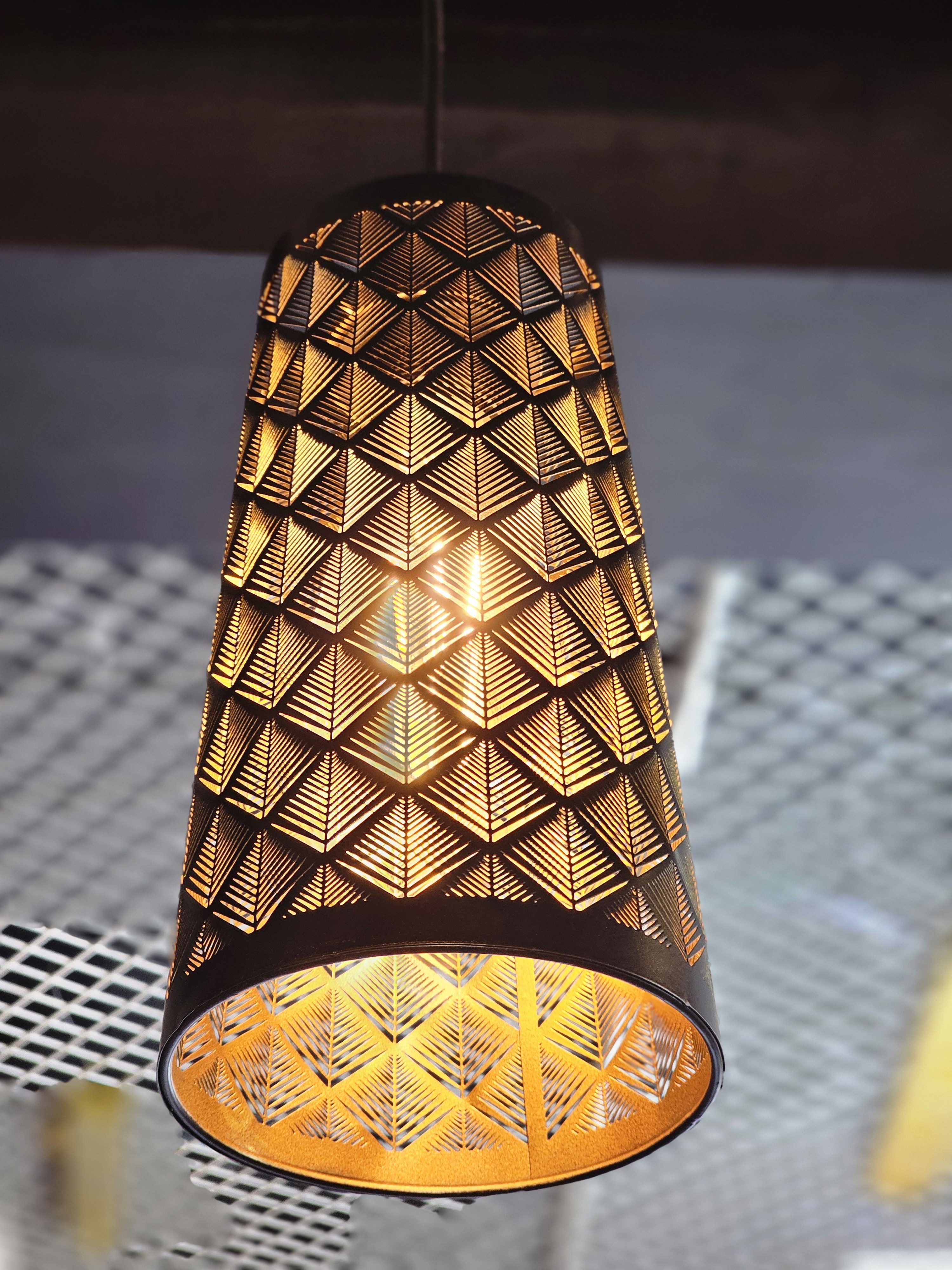 A hanging lamp with a geometric design casts a warm glow. Captured from an electrical shop in Kozhikode.