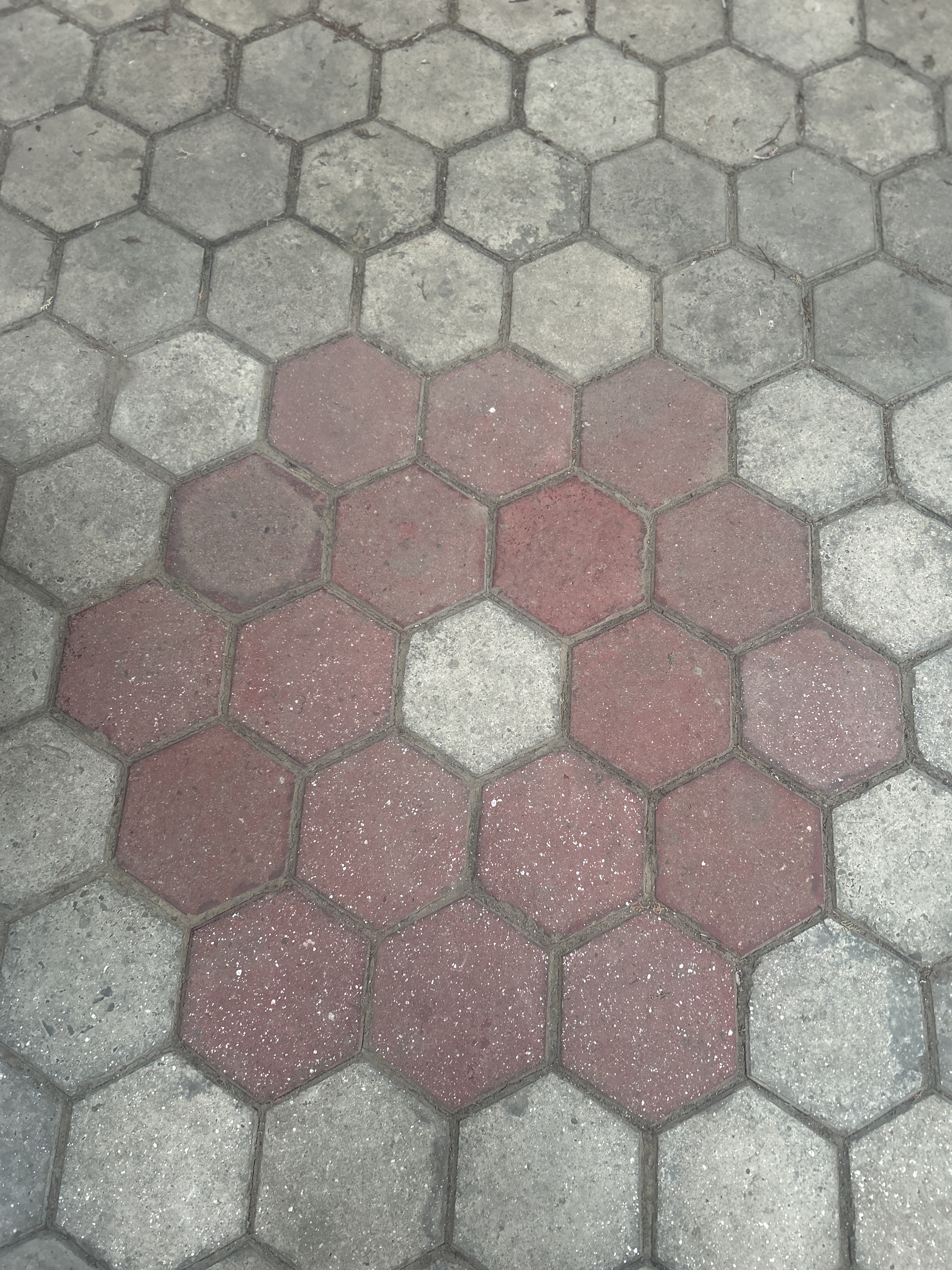 Hexagonal pavement tiles in a pattern, predominantly gray with a center cluster of red tiles.