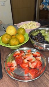  A table displaying a bowl of strawberries, oranges, and grapes alongside a bowl of popcorn.

