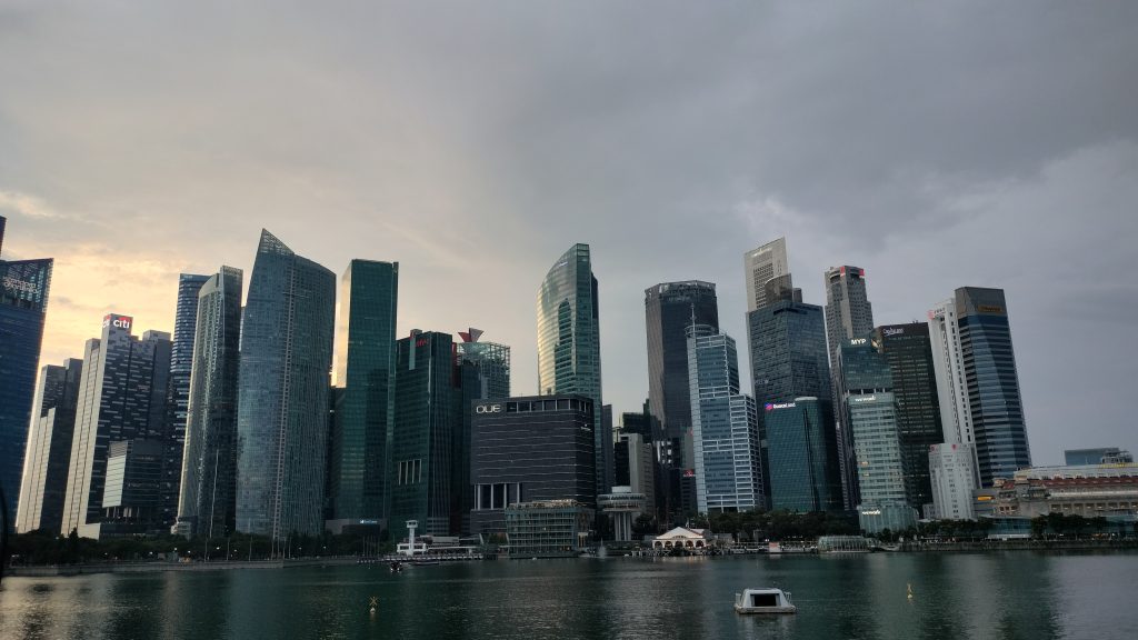 Modern skyline of Singapore’s Marina Bay at sunset, showcasing towering skyscrapers and their reflections on the waterfront.