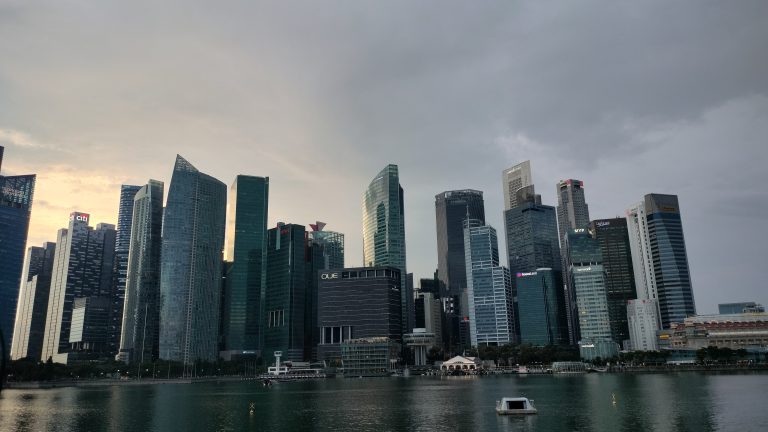 Modern skyline of Singapore’s Marina Bay at sunset, showcasing towering skyscrapers and their reflections on the waterfront.