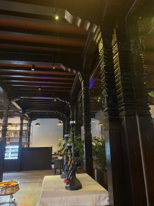 A cozy restaurant interior featuring ornately carved wooden pillars and beams. 