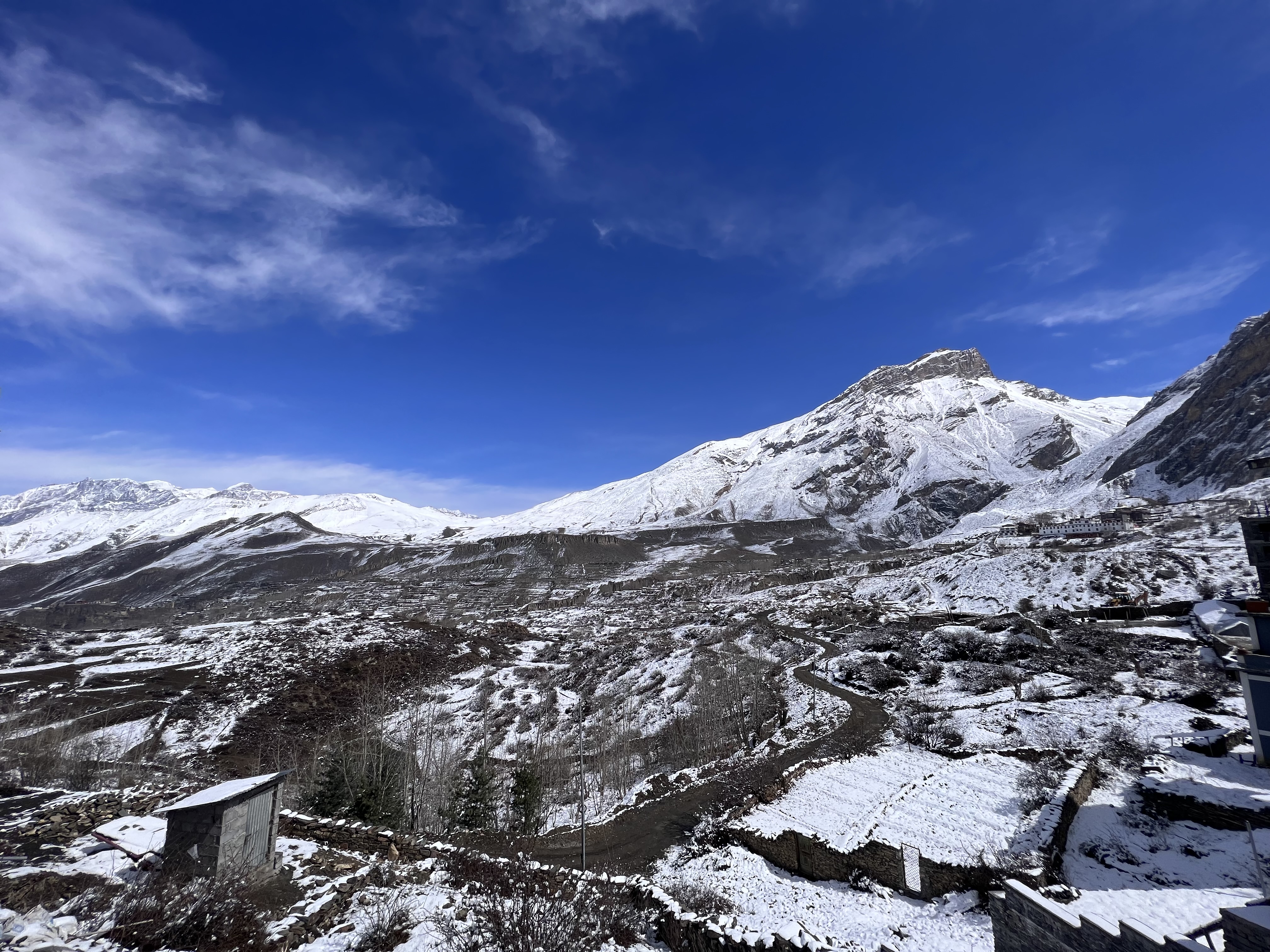 A vast mountainous landscape covered in snow under a bright blue sky.