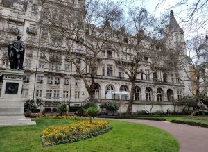 A historical building with ornate architecture stands behind a formal garden