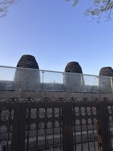 A view of three cylindrical, brick structures topped with domed covers behind a glass railing.