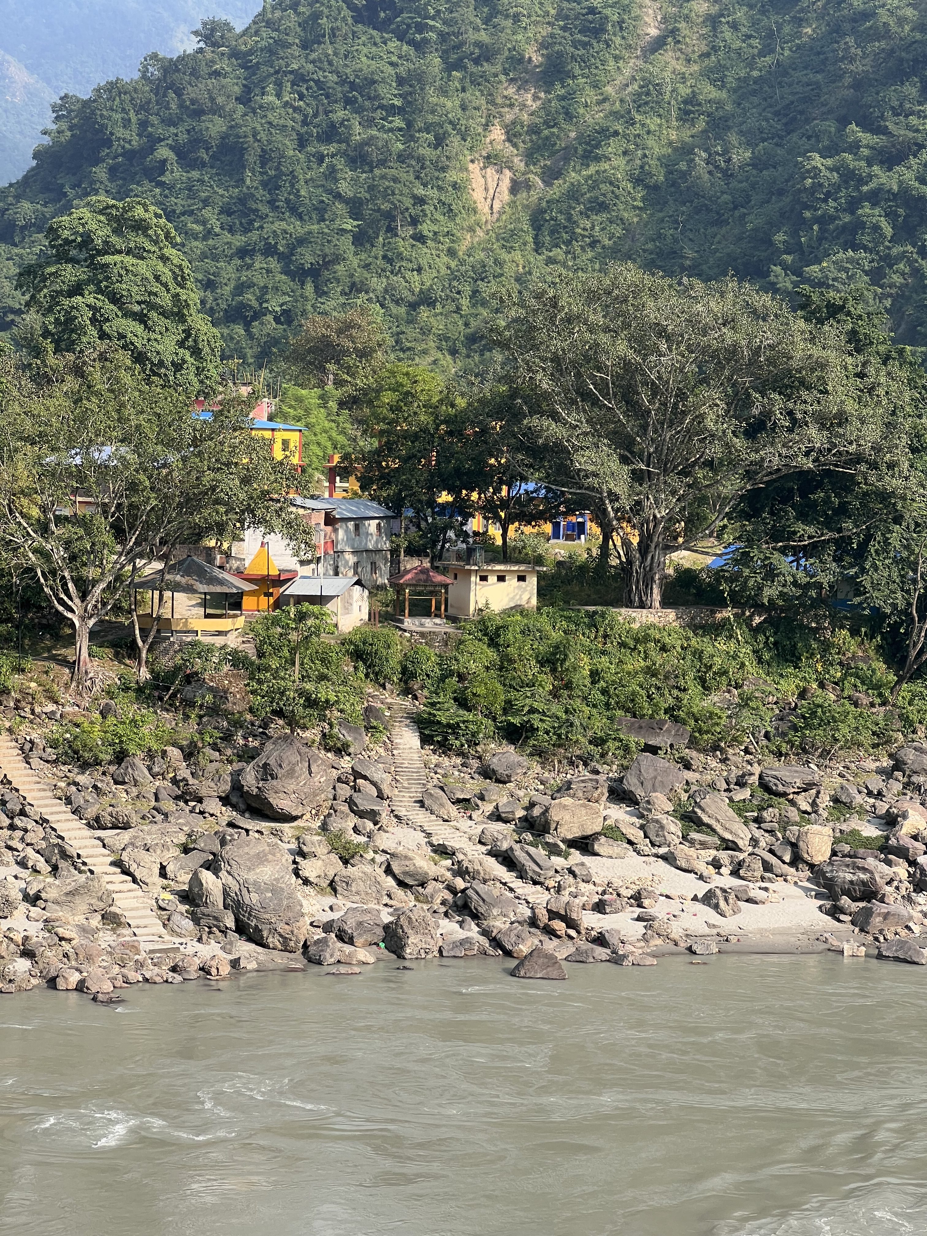 Hindu Temple premises on the bank of a river and surrounded by jungle. Staircase helps pilgrims to reach the river where they take bath before worshiping the temple.