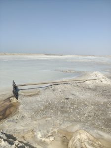 A wide, flat expanse of a salt flat under a clear blue sky.

